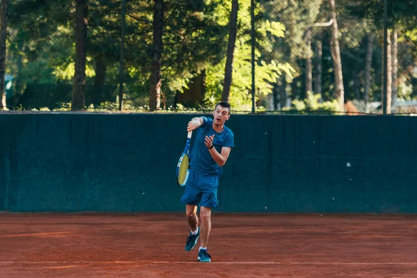 A professional tennis player is serving ball on a clay tennis court