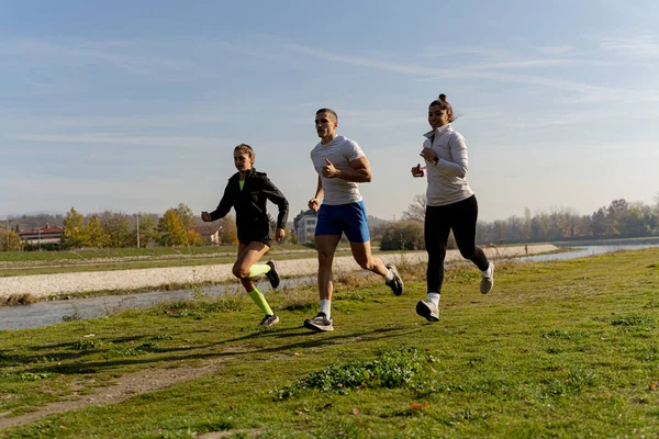 Trzy Niesamowite Atrakcyjne Przyjaciele Jogging Razem Pobliżu Rzeki Podczas Korzystania — Zdjęcie stockowe