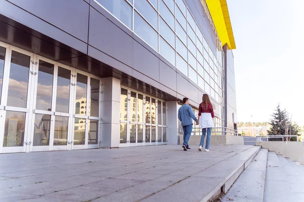 Cute couple walking away while holding hands from behind