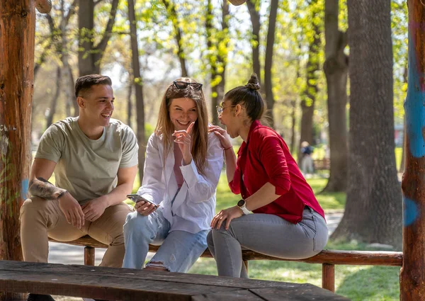 Three Happy Friends Watching Media Content Smart Phones Sitting Bench — Stok fotoğraf