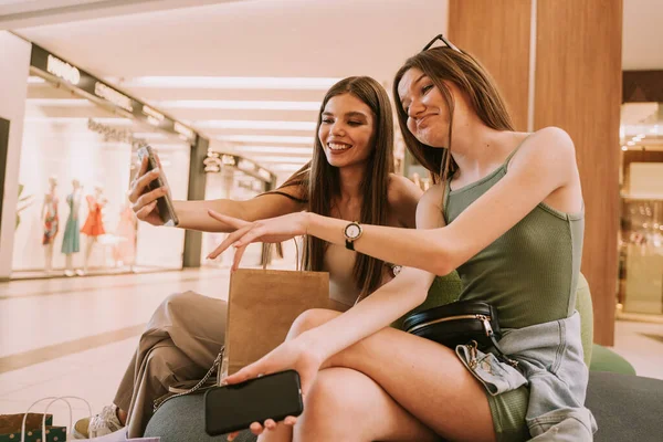 Two Cute Girls Looking Laughing Phone While Sitting Sofa Mall — Foto Stock