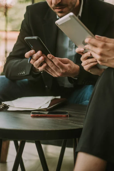 Business people looking at the phone and tablet while sitting at the cafe