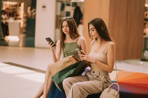 Cute Shopping Girls Sitting Sofa Mall While Looking Phones — Photo