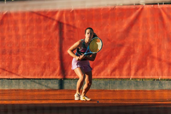 女子学生服姿の白人女性が粘土コートでテニスをする — ストック写真