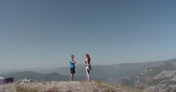 夏の日に山の上でヨガを練習するカップル — ストック動画