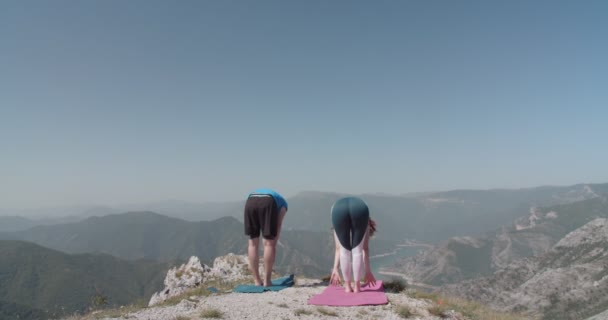 夏の日に山の上でヨガを練習するカップル — ストック動画