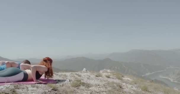 山の上でヨガの準備をしているカップル カメラが彼らの間を移動し ズームアウト — ストック動画