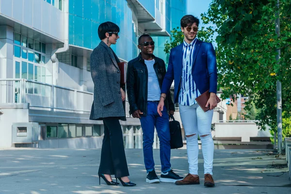 Group of well-dressed multi-ethnic business partners discussing a project outdoors