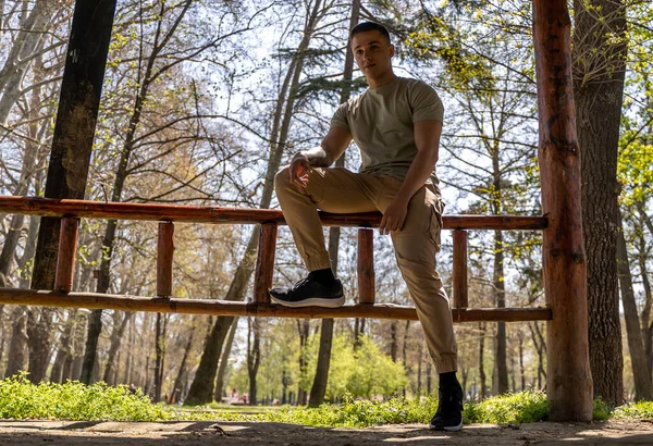 Image of a young strong happy cheery sports man posing outdoors in nature green park looking camera