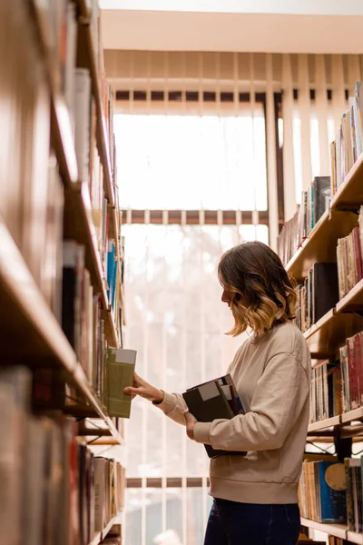 Girl putting back a book  on the bookshelves in the library