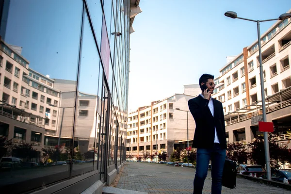 Businessman with his phone walking near the building