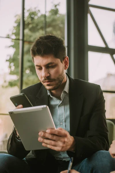 Hombre Negocios Mirando Teléfono Mientras Sostiene Tableta Café —  Fotos de Stock