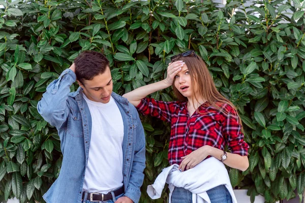 Cute couple worries about something while standing near the bush