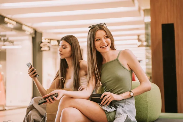 Dos Chicas Guapas Sentadas Sofá Centro Comercial Una Ellas Mirando — Foto de Stock