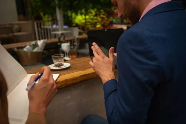 Ein Junger Geschäftsmann Checkt Sein Telefon Während Seine Mitarbeiterin Notizen — Stockfoto