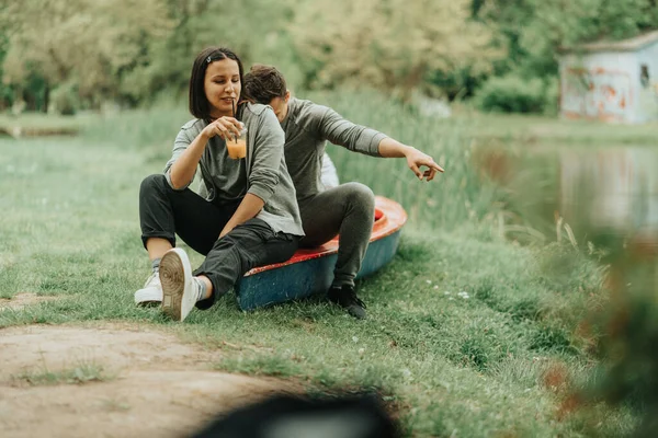 美丽的一对情侣坐在公园里的红皮划艇上悠闲自在 — 图库照片