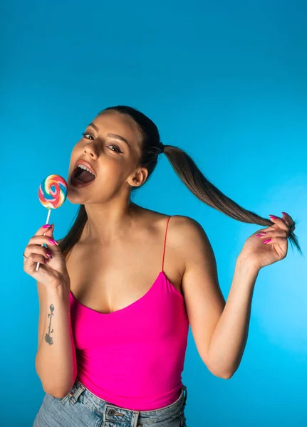 Cutel Dziewczyna Pozowanie Lizakiem Niebieskim Zapleczu Studio Trzymając Jej Włosy — Zdjęcie stockowe