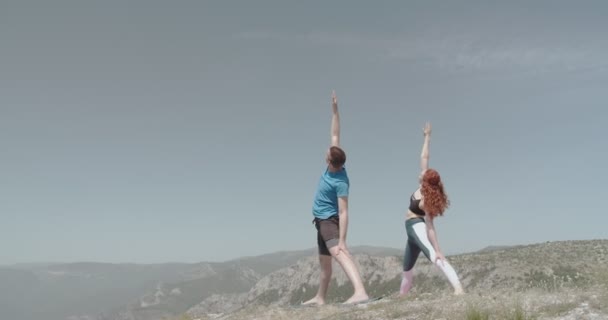 山の上でヨガを練習している二人 — ストック動画