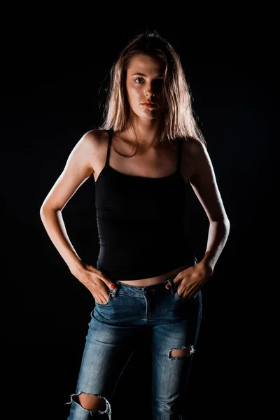 スタイリッシュなデニムパンツとブラックタンクトップを身に着けている現代の女の子のスタジオファッションの肖像画 — ストック写真