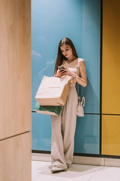 Menina Bonito Inclinando Parede Shopping Enquanto Olha Para Telefone — Fotografia de Stock