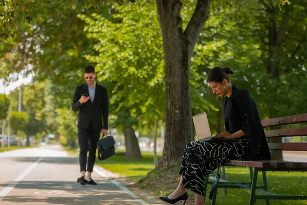 ハンサムな男性実業家が彼女の前を通過している間 豪華な実業家は ベンチに座って 屋外で働いている — ストック写真