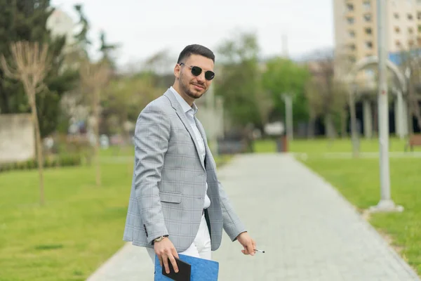 Handosme and urban businessman is smiling while holding his documents