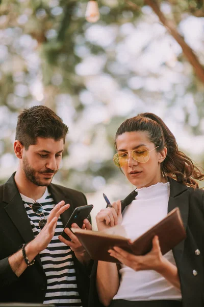 Zblízka Dva Obchodní Partneři Stojící Dívající Poznámky Notebooku Telefon — Stock fotografie