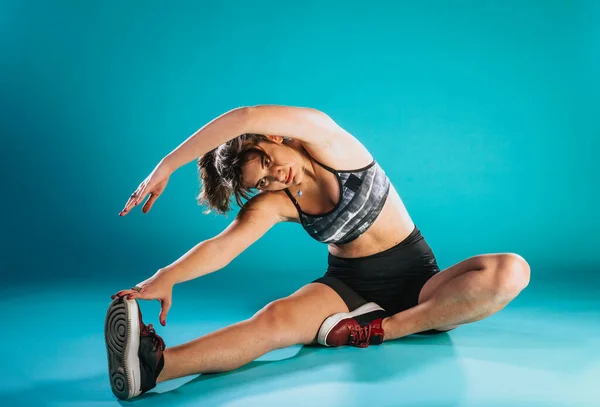 Beautiful sport woman in sportswear working out doing stretching sports exercises on light blue background