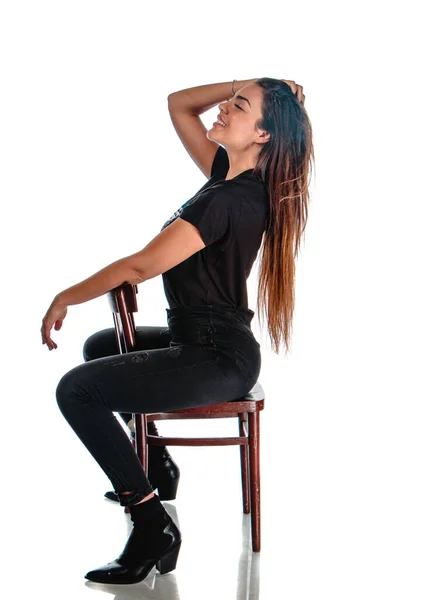椅子に座っている間にスタイリッシュな服を着た魅力的な女性のスタジオボディショット — ストック写真