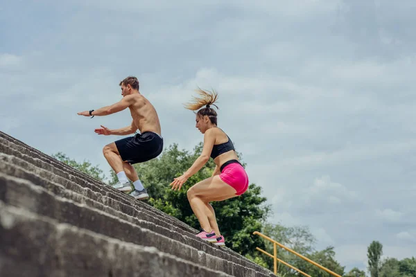 Poniżej Widok Młodych Mężczyzn Kobiet Sportowców Skaczących Górę Schodach Zewnątrz — Zdjęcie stockowe