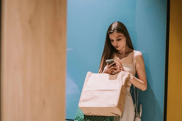 Güzel Kız Telefonuna Bakarken Alışveriş Merkezinin Duvarına Yaslanıyor — Stok fotoğraf