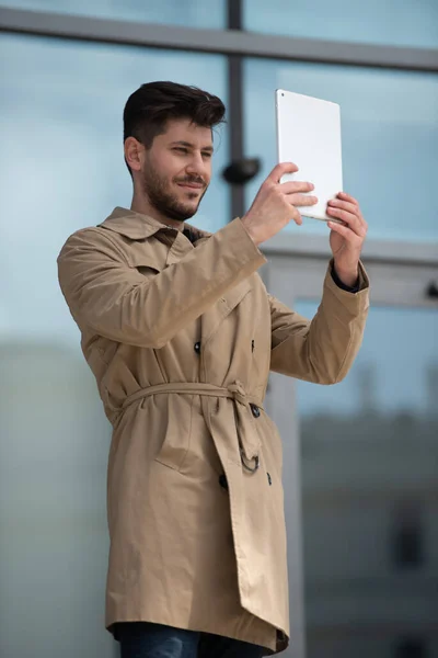 Urban businessman is smiling while looking at the plans and ideas on his tablet