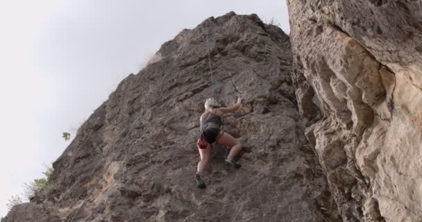 魅力的な女の子はロープで友人から手を助けることで大きな岩に登っている — ストック動画