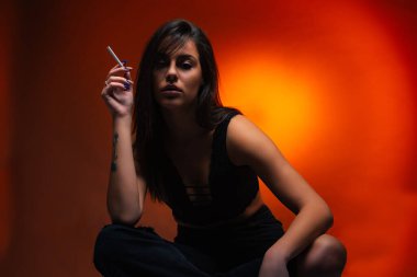 Attractive and beautiful hot girl is posing on the ground while looking seductive with the cigarette clipart