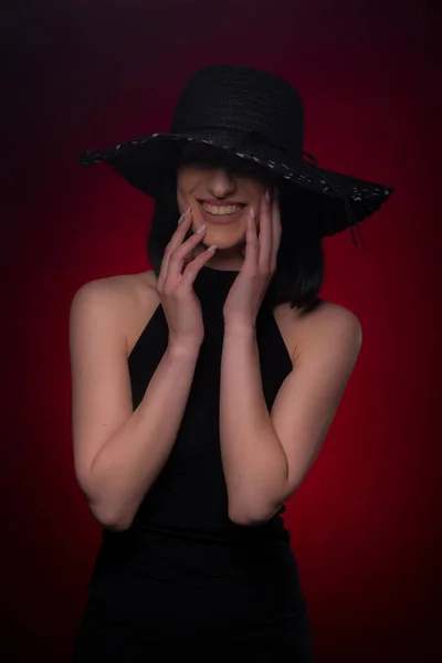 Záhadná Dívka Pózování Černých Šatech Červeném Pozadí Zároveň Usmívá — Stock fotografie