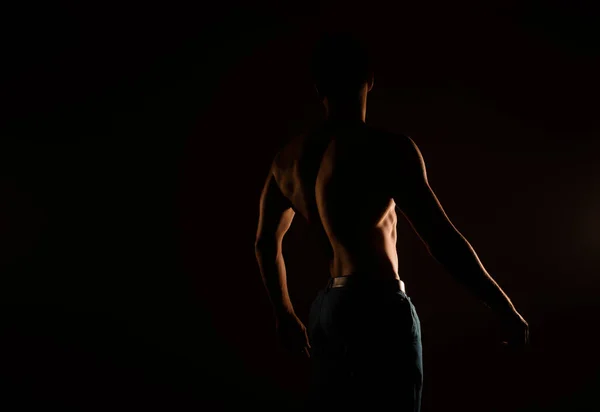 Silhouette of handsome man's back standing in the studio