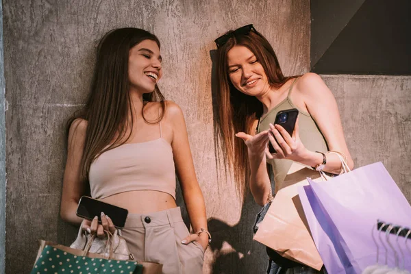 Dos Hermosas Hermanas Jóvenes Riéndose Teléfono Mientras Sostienen Bolsas Con —  Fotos de Stock