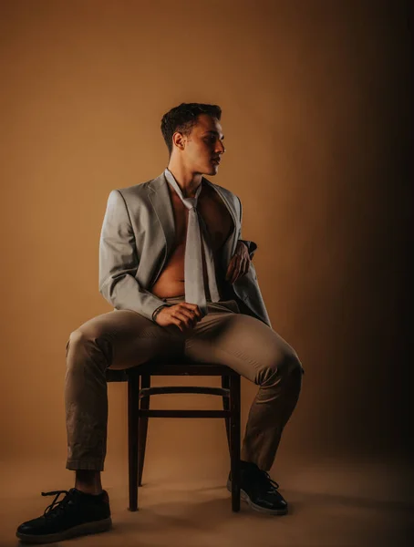 スタジオで椅子に座っている間にハンサムな男性モデルポーズ — ストック写真