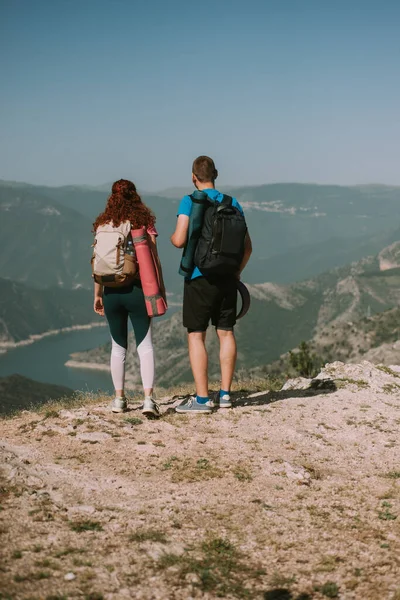 山に立っている間に湖を見て驚くべきヨガのカップル — ストック写真