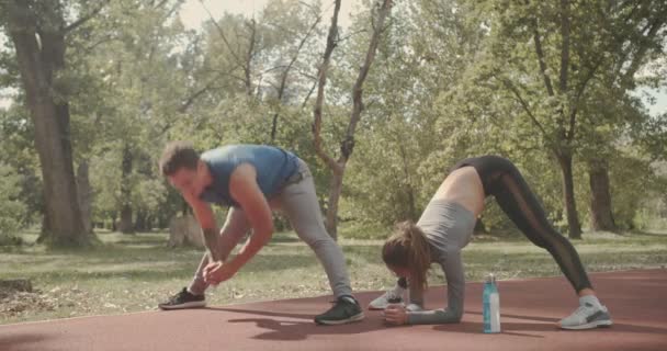年轻夫妇在公园锻炼前伸展着身体 秋天的日落 — 图库视频影像