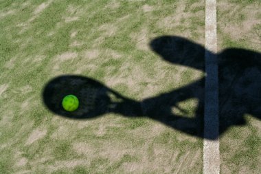 Padel raketinin gölgesi ve sahadaki oyuncu.