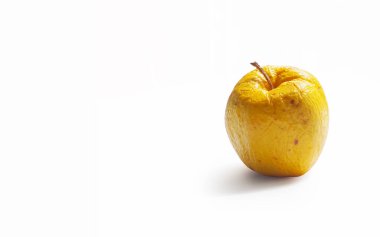 Kırışık ve pörsümüş sarı bir elma. Pazarlanabilir görünümünü kaybetmiş. Beyaz bir arka planda izole edilmiş..