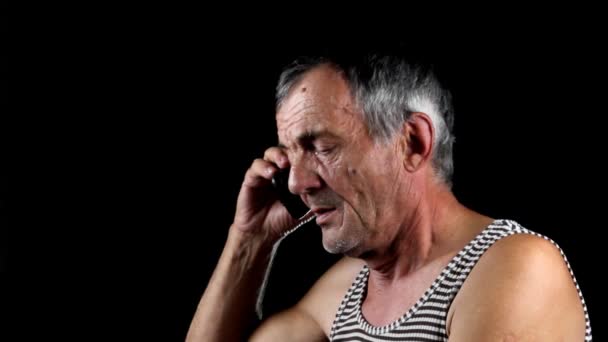 Старший разговаривает по мобильному телефону на черном фоне — стоковое видео