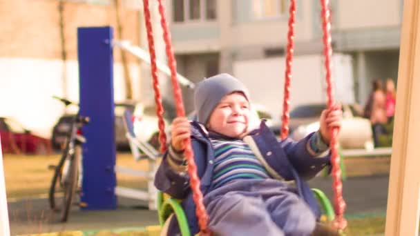 Niño montando en un columpio — Vídeo de stock