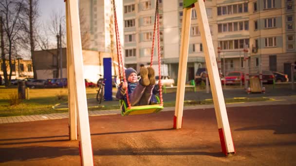 Хлопчик їде на гойдалці — стокове відео