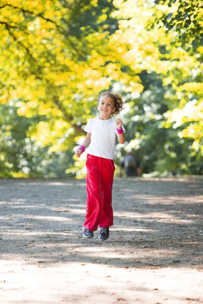 Tyttö juoksee puistossa — kuvapankkivalokuva
