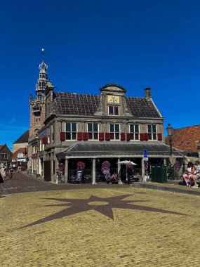 MONNICKENDAM, NETHERLANDS - AUGUST 10, 2022: Historic house facades located at the harbor of Monnickendam, North Holland, Netherlands, with the spire and clock tower of Speeltoren 