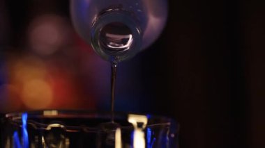 lcohol is poured into a bar glass from a chilled bottle. Close-up, bokeh, rotated subject