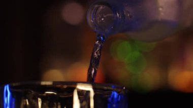 lcohol is poured into a bar glass from a chilled bottle. Close-up, bokeh, rotated subject