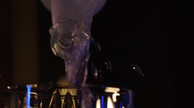 Alkol bir bardağa şişeden çıkan insanlarla doldurulur. Yakın çekim, döndürülmüş nesne